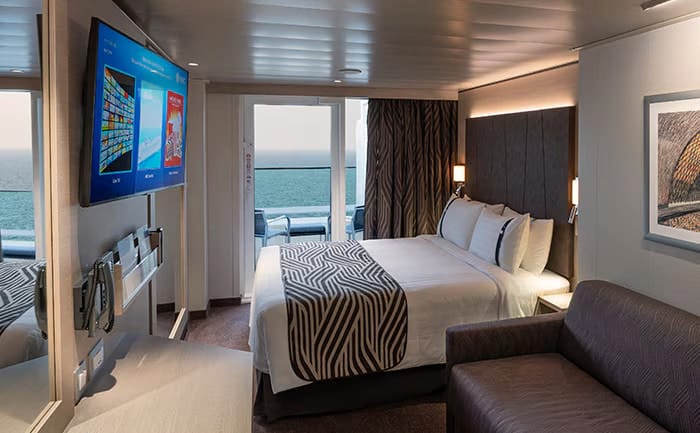 What Cruise Cabin Should You Book? A First-Timer's Guide 4 MSC premium suite with king bed, sofa, flat-screen TV, and balcony overlooking the ocean.