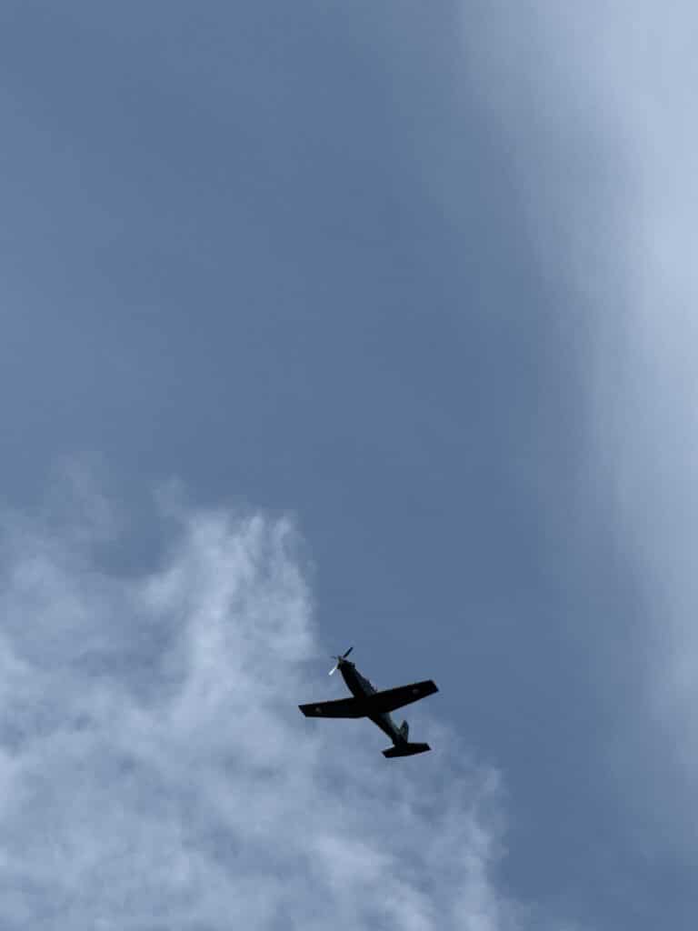small-single-engine-airplane-flying-clear-blue-sky.jpeg Small single-engine airplane flying in a partly cloudy blue sky during daytime flight travel in Anglesey, RAF Alley